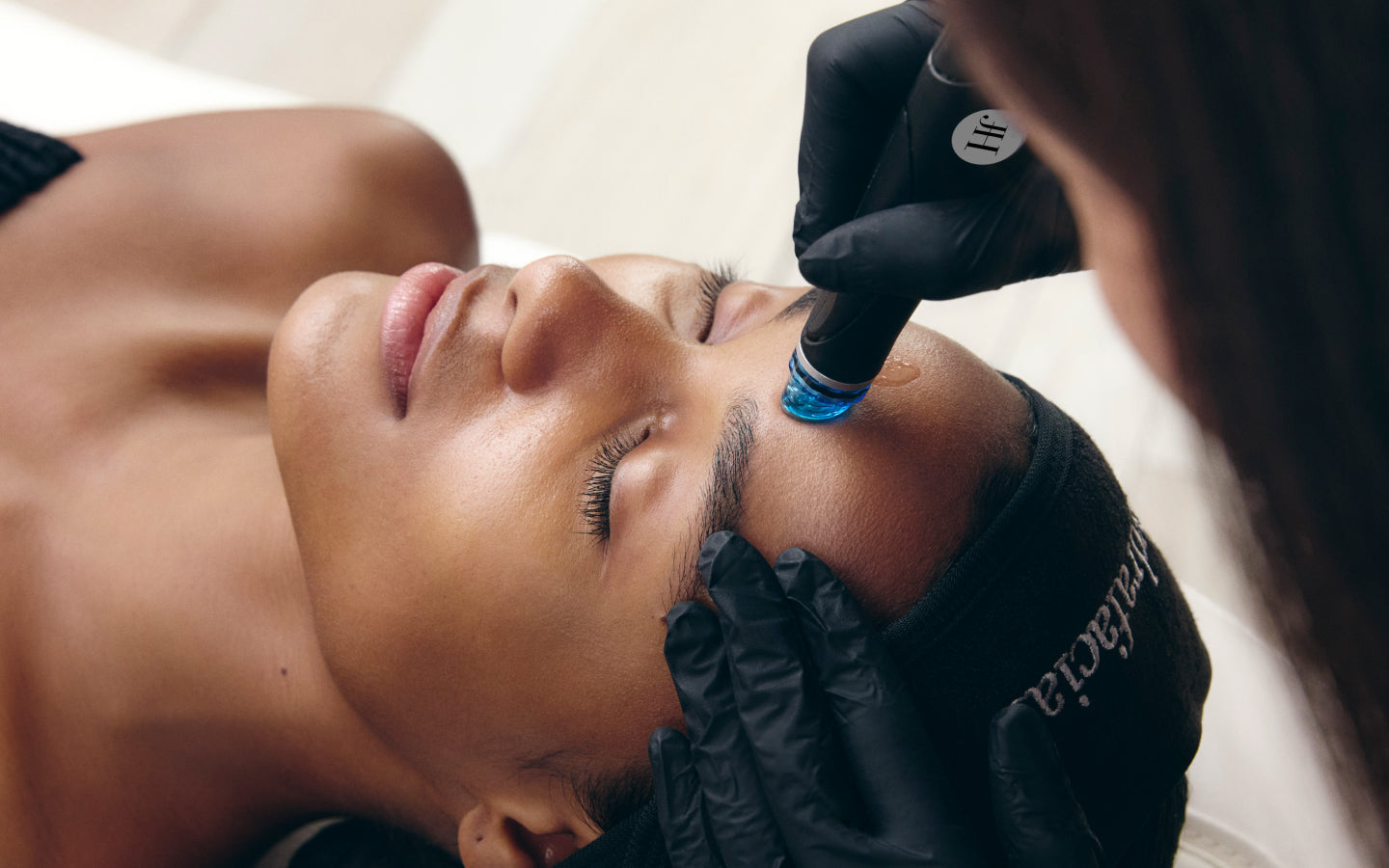 Provider performing a Hydrafacial treatment on a client’s forehead.